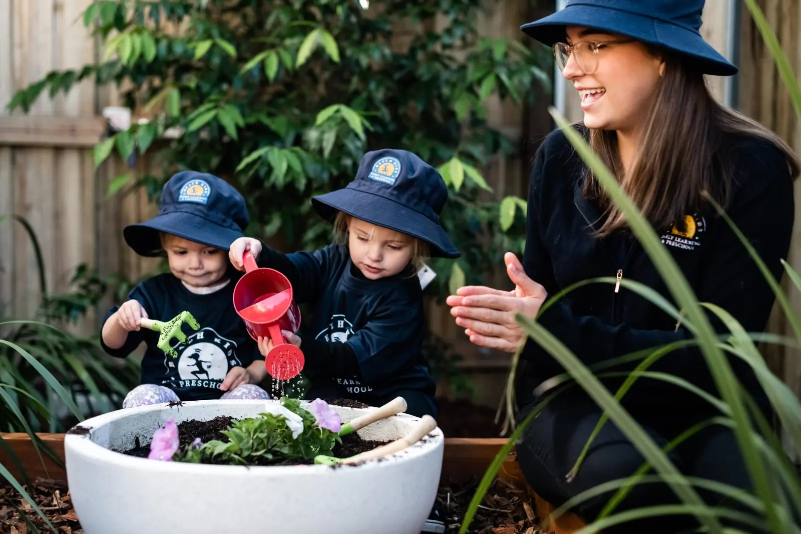 An educator and children planting in the Chinderah garden