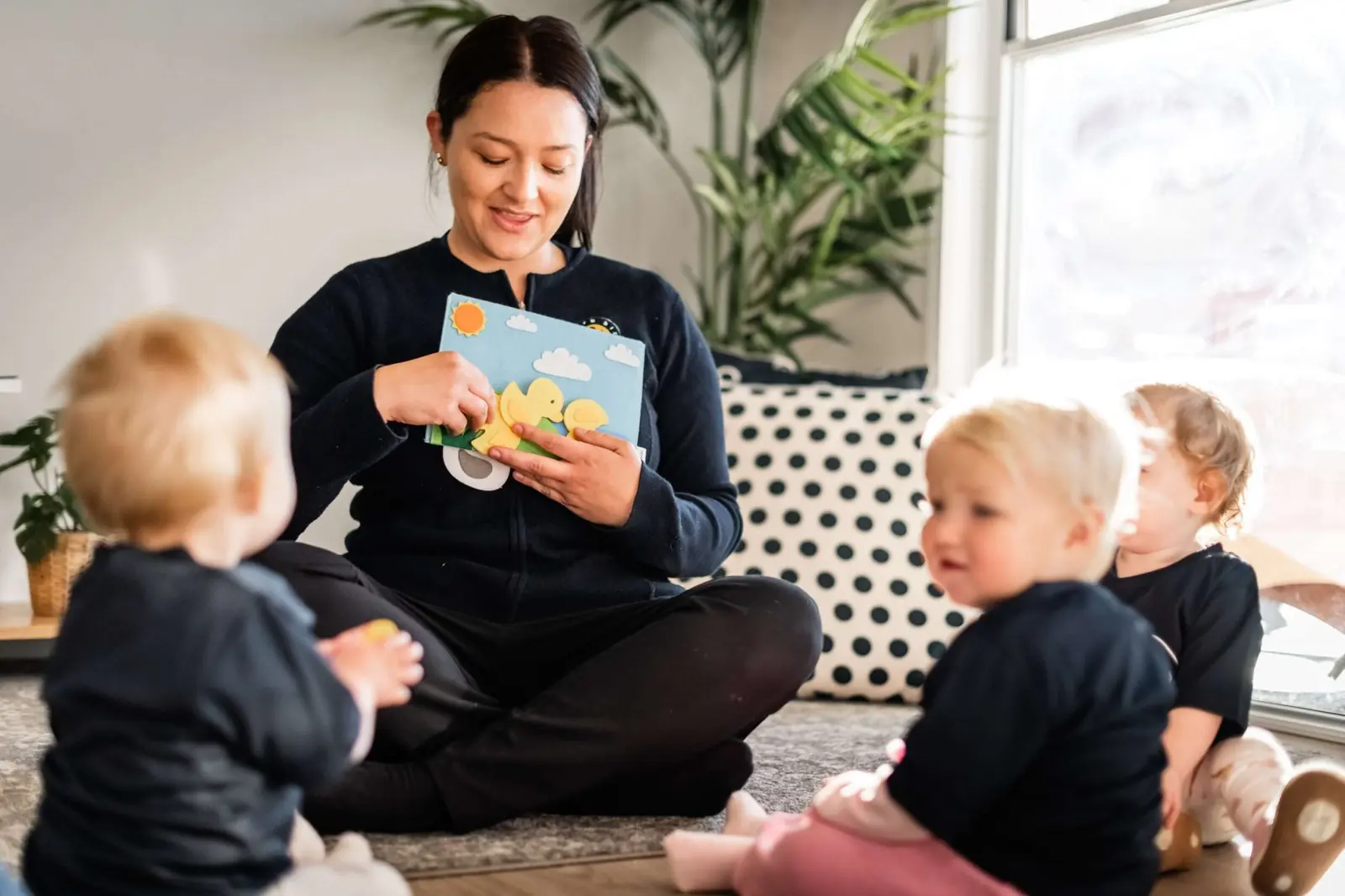 An educator reading to toddlers on the mat at Chinderah