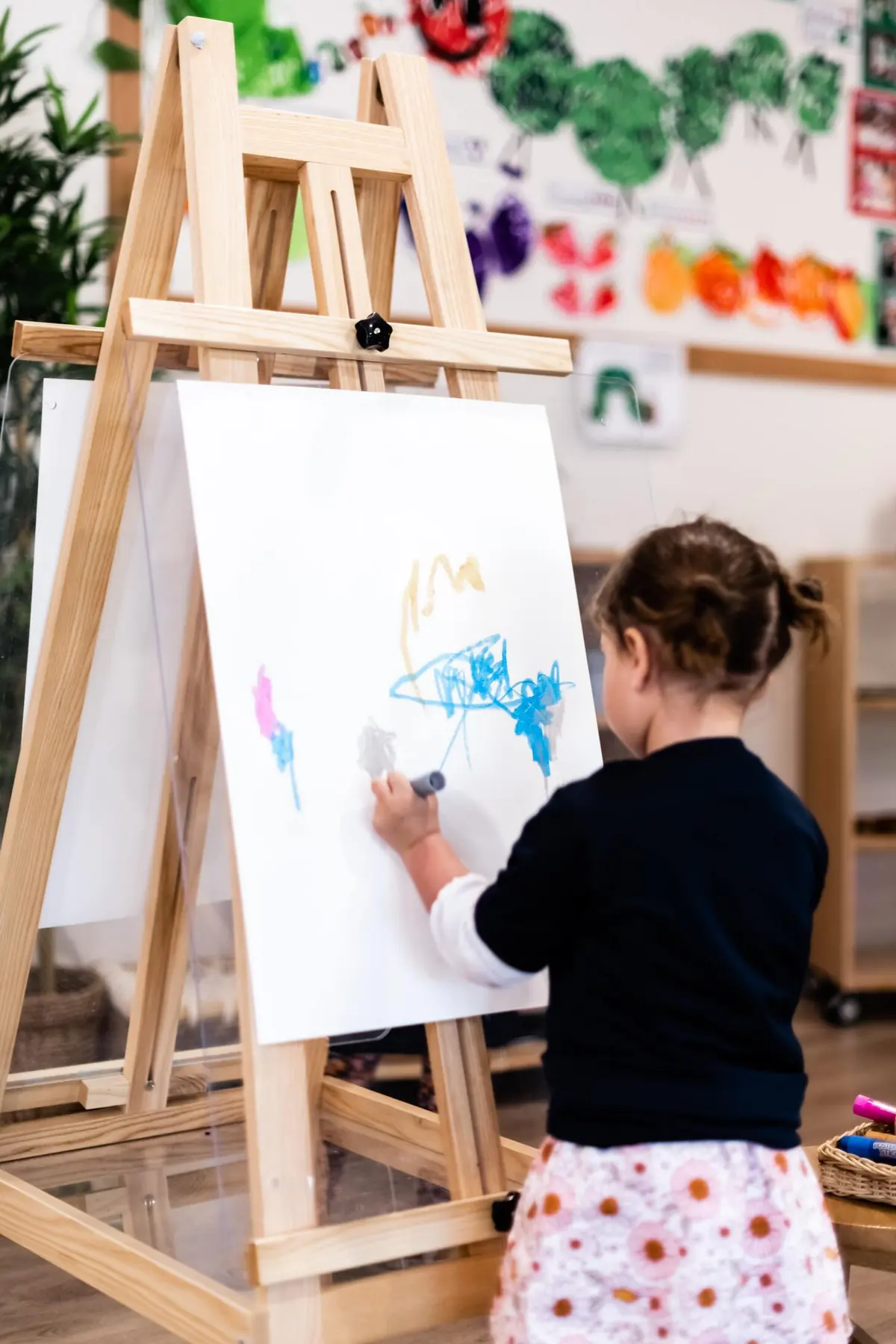 A child painting at an easel at Beach Kids Chinderah