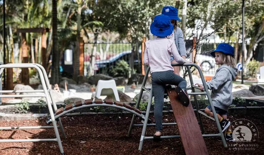 Children balancing along a timber beam in the outdoor play area