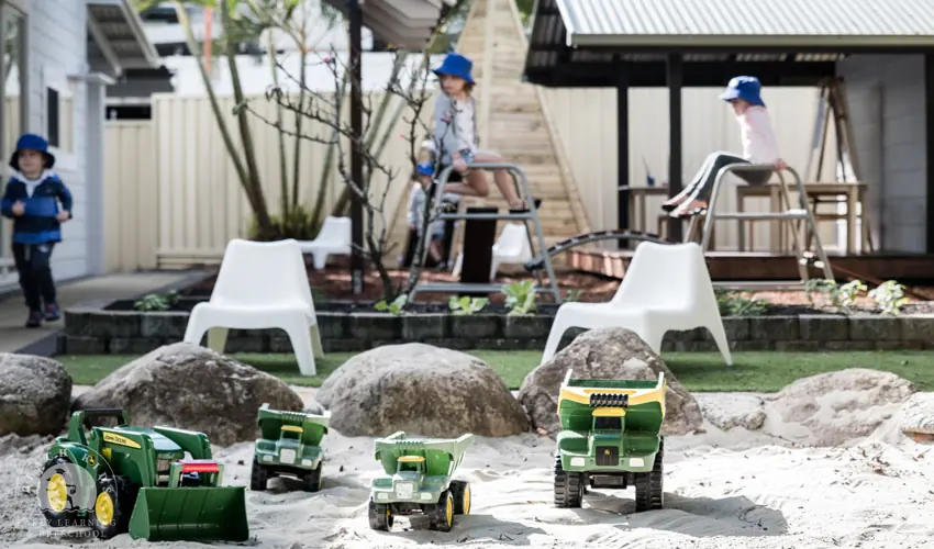 Children digging with toy trucks in the sandpit