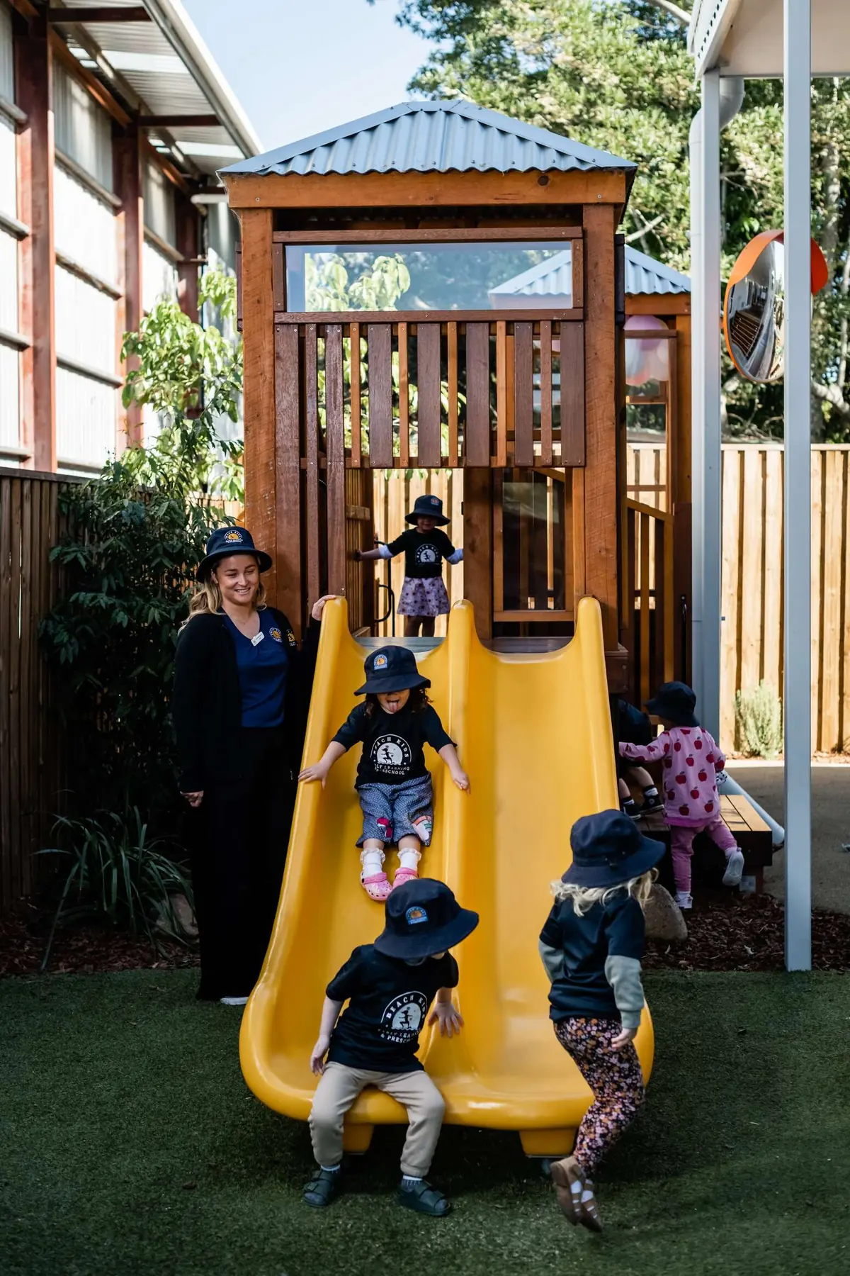 A child going down the yellow slide at Beach Kids Chinderah