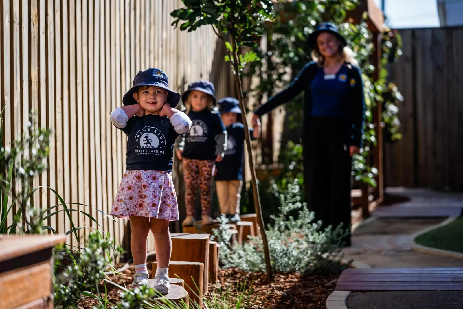 A child crossing timber stepping logs with an educator nearby