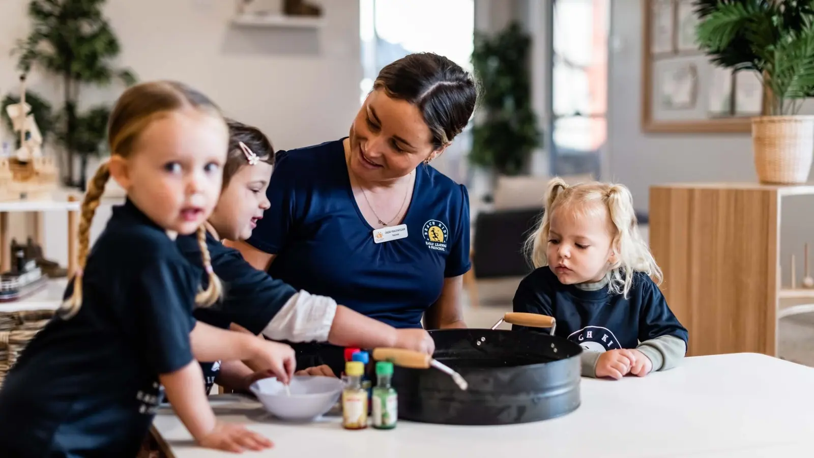 An educator and children cooking together at Beach Kids Chinderah